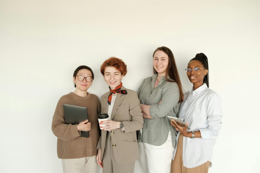 Group of professional women in business attire standing against a white background.